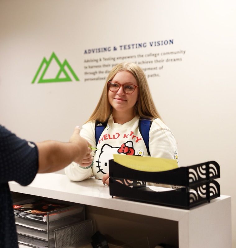 Student shaking hands with a PPSC advisor at the Advising & Testing counter